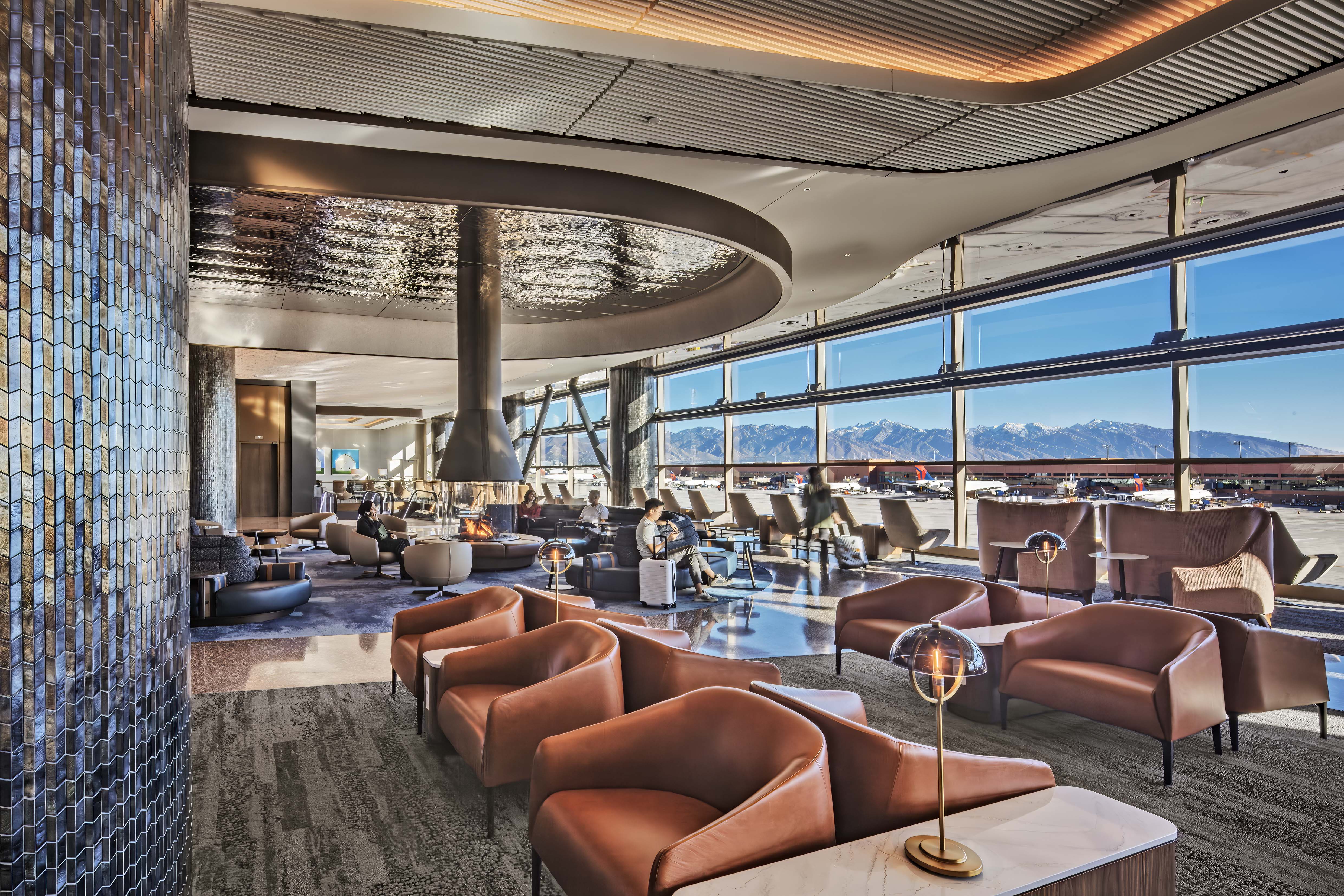 View of the Wasatch Mountain Range from inside the central lounge with the 360-degree fireplace in the new Delta Sky Club in Salt Lake City International Airport's concourse B.