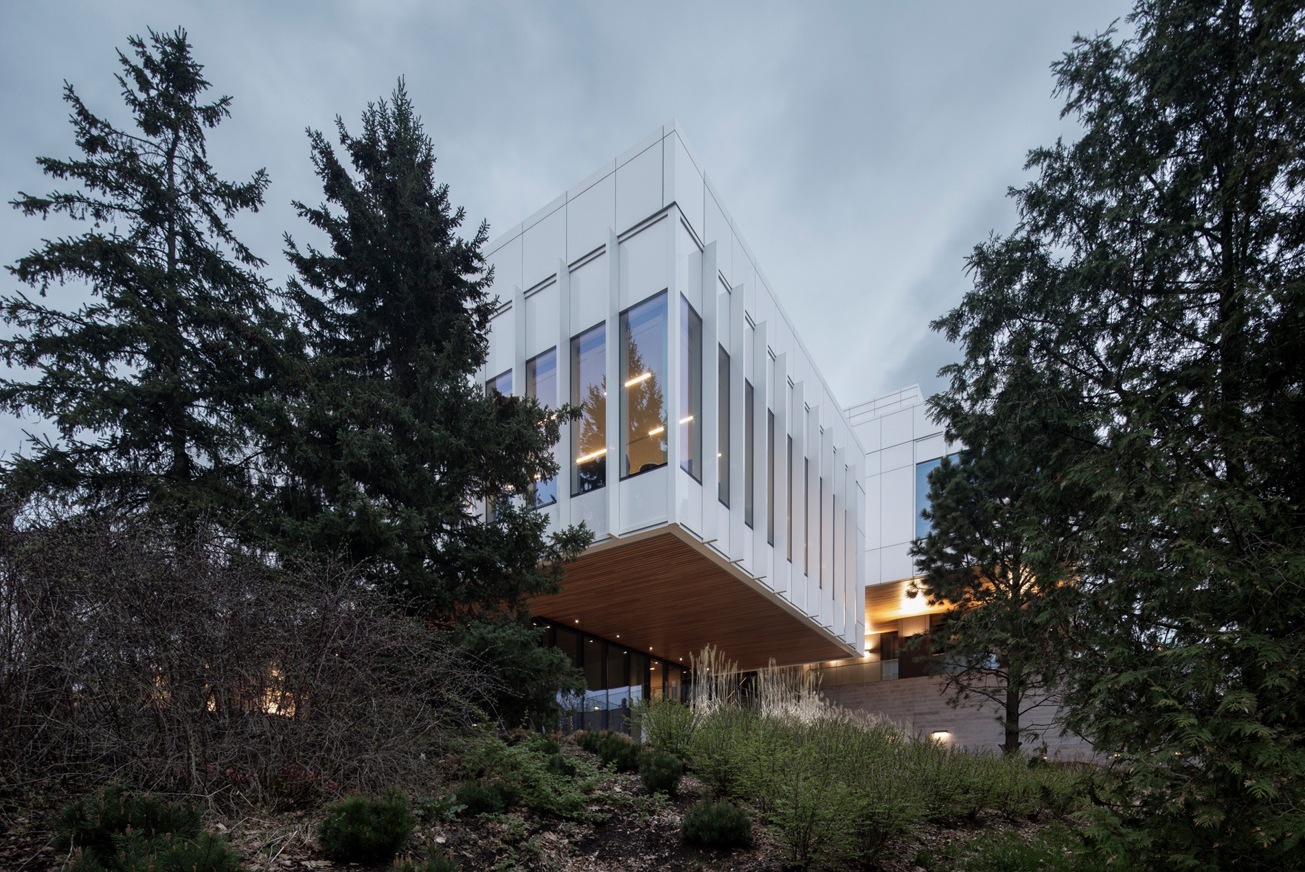 HOK-designed British High Commission exterior at dusk, surrounded by trees and woodlands next to the National Capital Commission parkland.