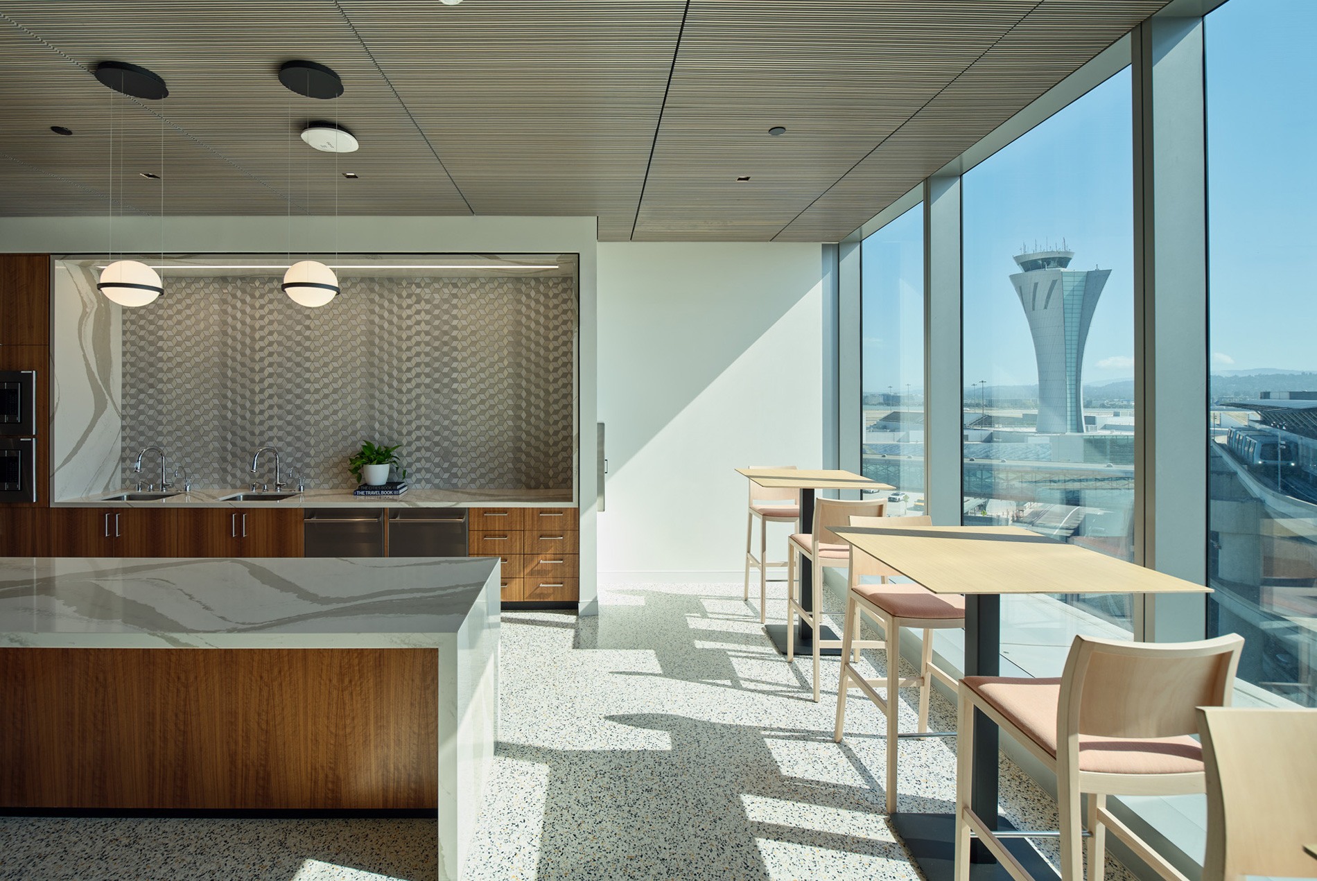 Kitchen space with daylight coming through the full windows with the air traffic control tower in the background at the HOK-designed executive offices at San Francisco International Airport